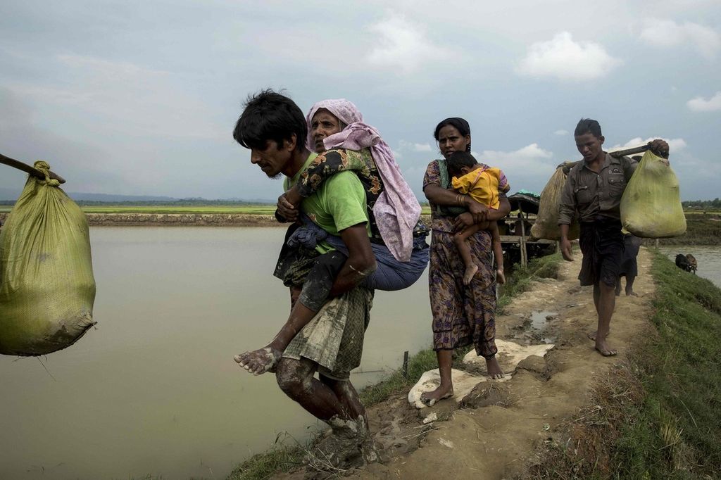 Pengungsi Rohingya asal Negara Bagian Rakhine, Myanmar, berjalan di dekat Ukhia, perbatasan Myanmar-Banglades, untuk menyelamatkan diri dari kekerasan di Rakhine, Senin (4/9).