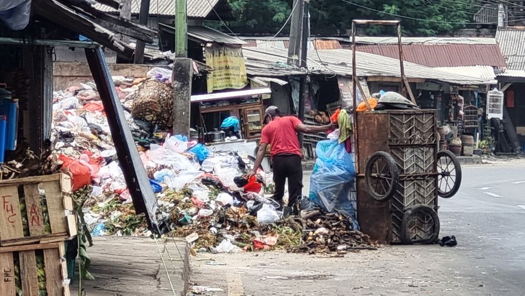 Seorang pendorong gerobak sampah sedang memunguti sampah berserakan di Pasar Cimanggis, Ciputat, Tangerang Selatan, Rabu (18/1/2023).