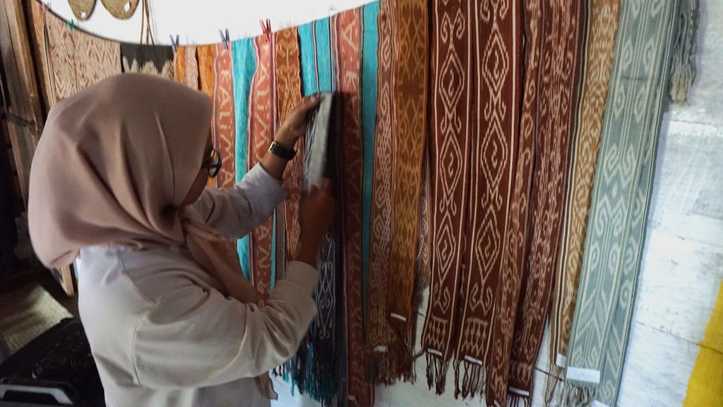 Salah seorang pembeli melihat kain tenun Dayak Iban di Dusun Ngaung Keruh, Batang Lupar, Kabupaten Kapuas Hulu, Kalimantan Barat, Sabtu (5/2/2022), Semua proses pewarnaan kain tenun Iban berasal dari tanaman dan produk alam.