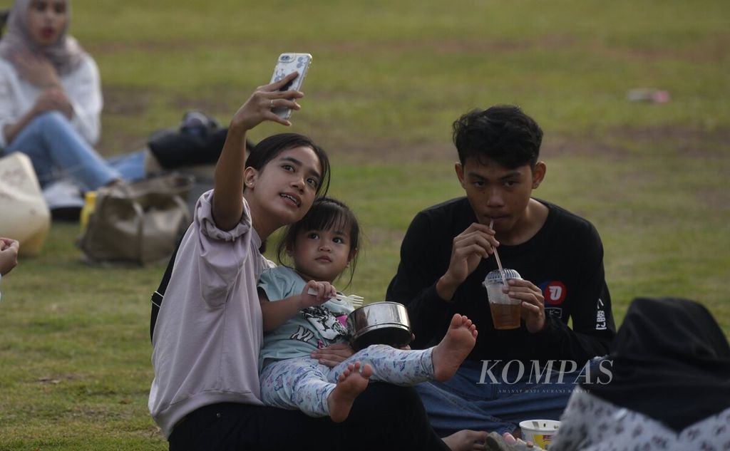 Keluarga bersantai menikmati suasana sore di Hutan Kota Gelora Bung Karno, Jakarta, Sabtu (18/3/2023). 