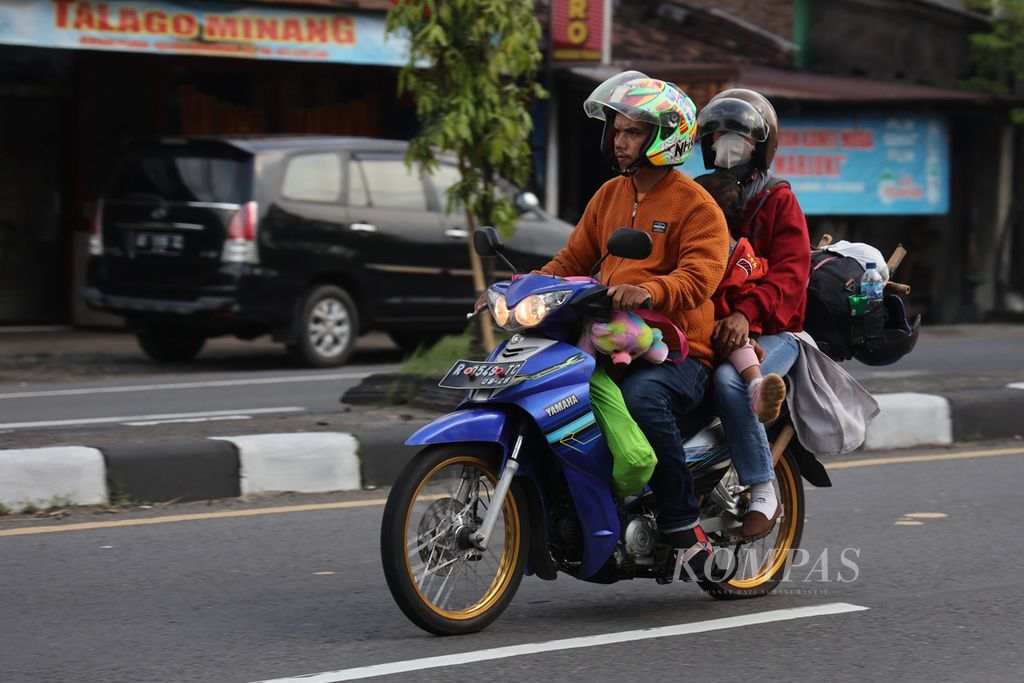 Miswono memboncengkan anak dan istrinya melintasi Jalan Raya Solo-Yogyakarta di Desa Gondang, Jogonalan, Klaten, Jawa Tengah, Jumat (5/5/2023). 