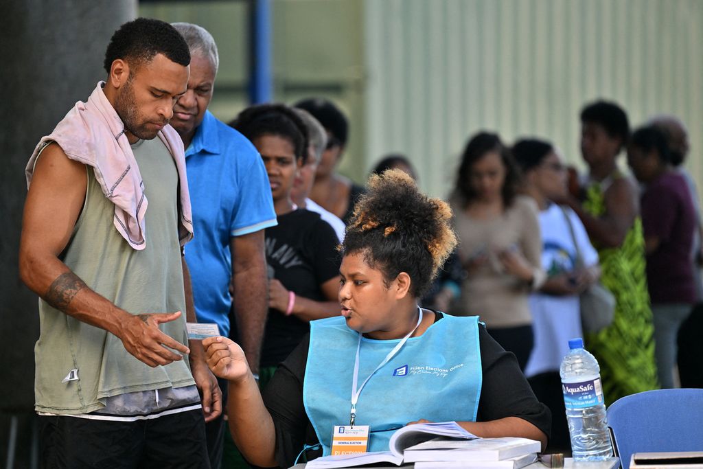 Seorang petugas tengah memeriksa nama calon pemilih di sebuah tempat pemungutan suara di Ibu Kota SUva, Fiji, Rabu (14/12/2022). Perdana Menteri Frank Bainimarama kembali mencalonkan diri untuk masa jabatan ketiganya dalam pemilihan kali ini. (Photo by SAEED KHAN / AFP) 