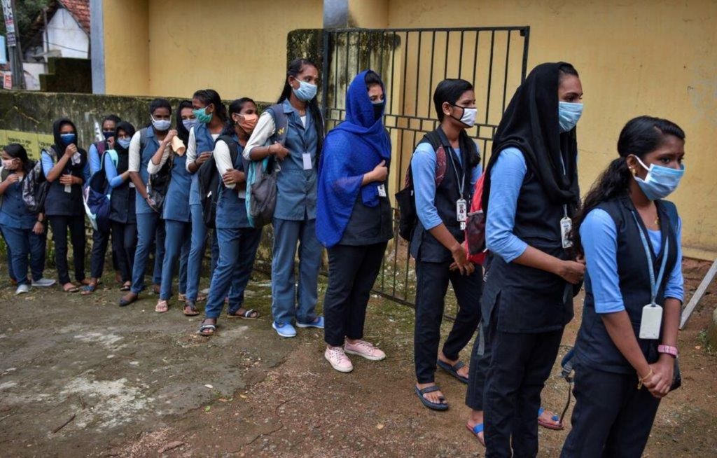Siswa berbaris sambil mengenakan masker untuk mendapatkan cairan pembersih tangan dan pengukuran suhu saat tiba di sekolah di Kochi, Negara Bagian Kerala, India, 26 Mei 2020.  