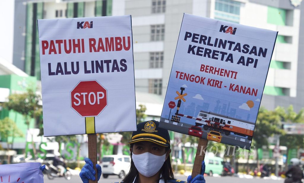Petugas membawa poster saat melakukan aksi simpatik Sosialisasi Keselamatan di Pelintasan Sebidang di Pelintasan Kereta Api Jalan Ahmad Yani, Surabaya, Jawa Timur, 14 Oktober 2020. 