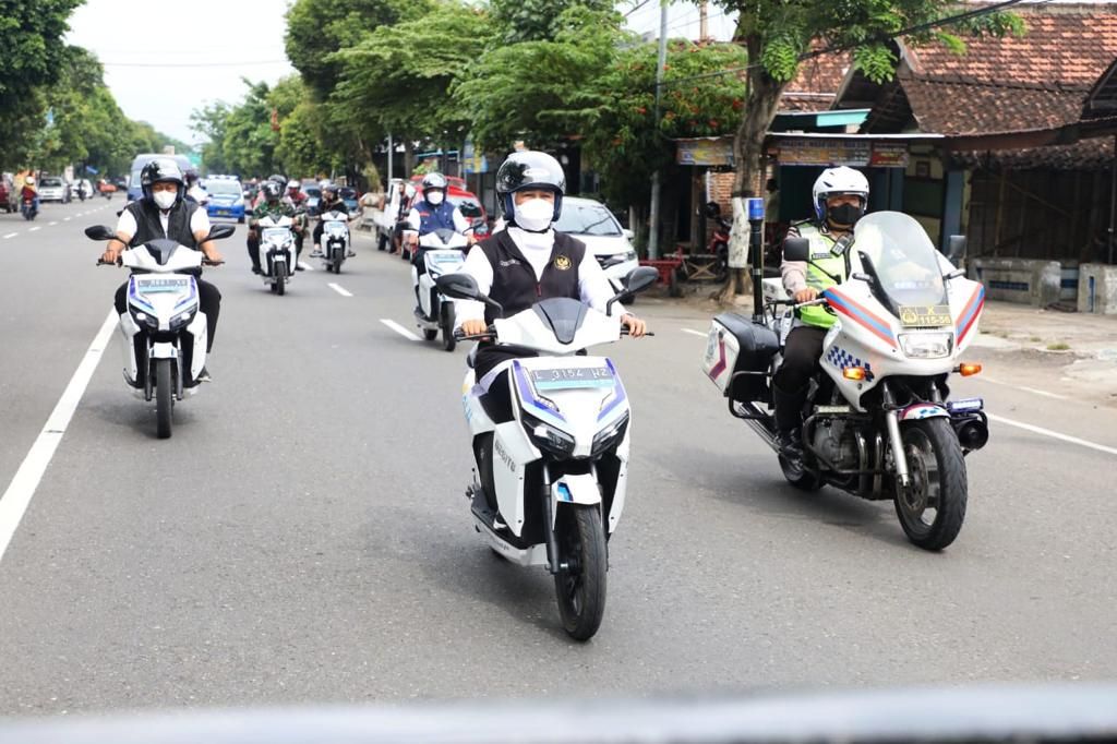Gubernur Jawa Timur Khofifah Indar Parawansa (tengah) mengendarai motor listrik keliling Surabaya, Rabu (23/3/2022).