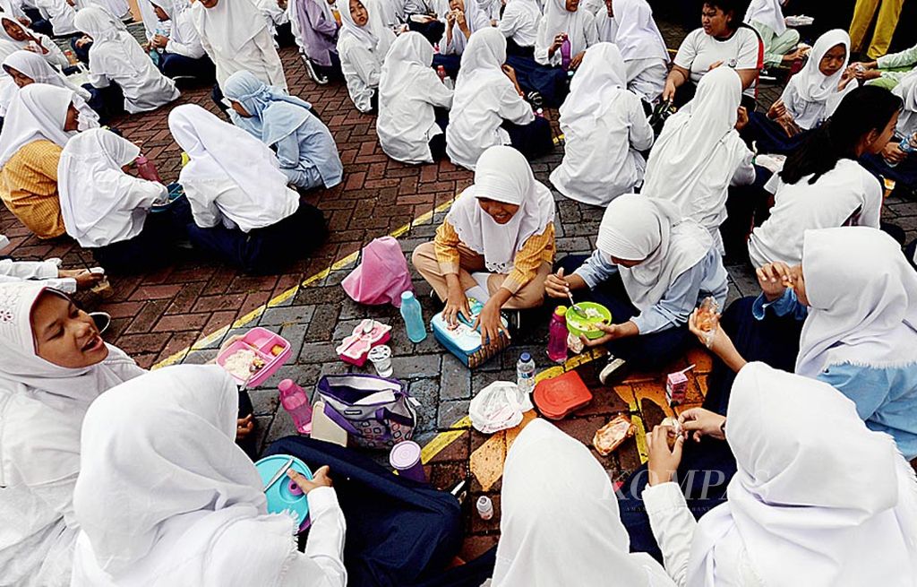 Para siswa  memanfaatkan jam istirahat untuk makan bersama di halaman  SMP Negeri 226 Jakarta Selatan, Jumat (21/7). Makan bersama menjadi tradisi untuk menjaga keharmonisan dan mempererat tali persaudaraan di sekolah yang memiliki 22 siswa berkebutuhan khusus tersebut.