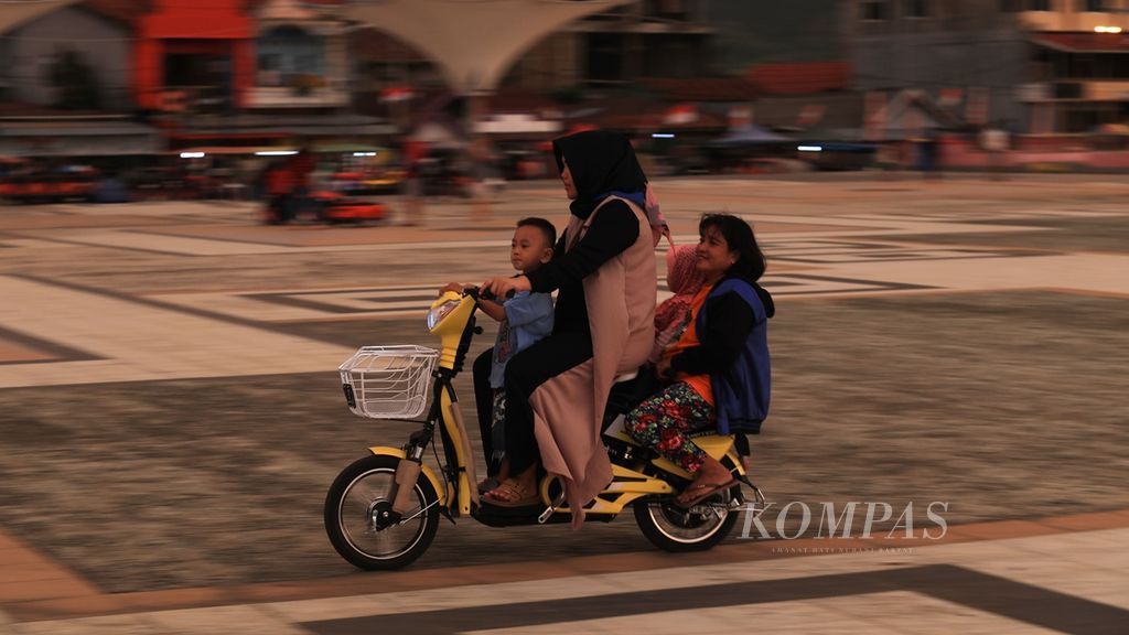 Ibu beserta anaknya menikmati sepeda listrik di Anjungan Pantai Manakarra, Kota Mamuju, Sulawesi Barat, Minggu (18/8/2019). Berbagai permainan anak-anak, seperti odong-odong, mobil <i>remote</i>, hingga sepeda, banyak disewakan di tempat ini. 