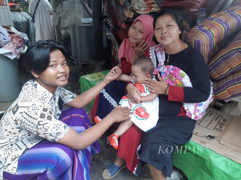 Ika (35) bersama anaknya di posko pengungsian, Pasar Gembrong, Jakarta Timur, pada Senin (2/5/2022).