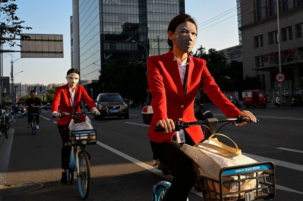 Perempuan, dengan mengenakan masker, mengendarai sepeda di sebuah ruas jalan di Beijing, China, 25 Juli 2023. 