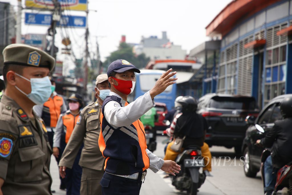 Petugas mengatur kelancaran lalu lintas di pos cek poin pemudik di jalan Ciledug Raya, Jakarta Selatan, Kamis (6/5/2021). 