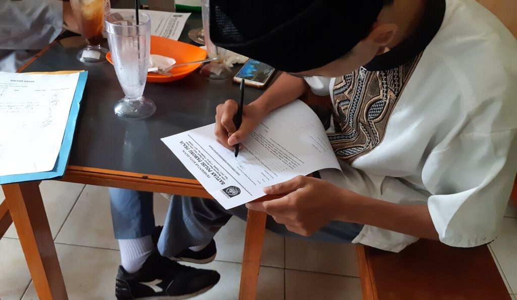 Seorang pelajar yang kedapatan membolos sedang menulis Surat Pernyataan Pelanggaran Disiplin Pelajar. Kedua siswa tersebut beralasan sedang ada Praktik Kerja Lapangan. Foto diambil pada 2019.