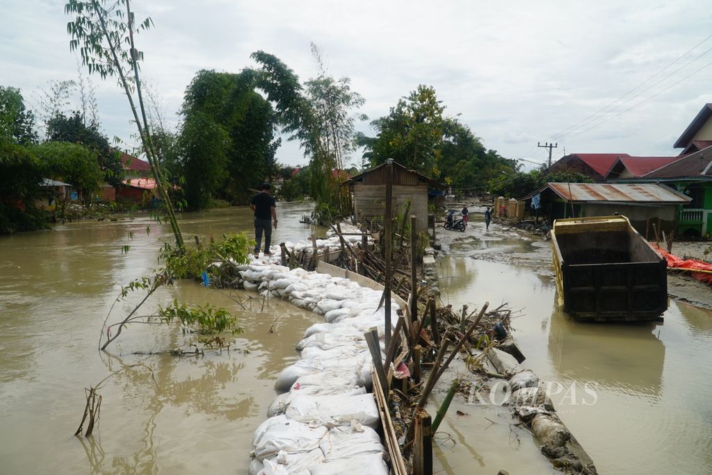 Karung berisi pasir menjadi tanggul darurat untuk menahan luapan air Batang Merao yang memicu banjir di Desa Tanjung, Kecamatan Hamparan Rawang, Kota Sungai Penuh, Jambi, Sabtu (20/1/2024). 