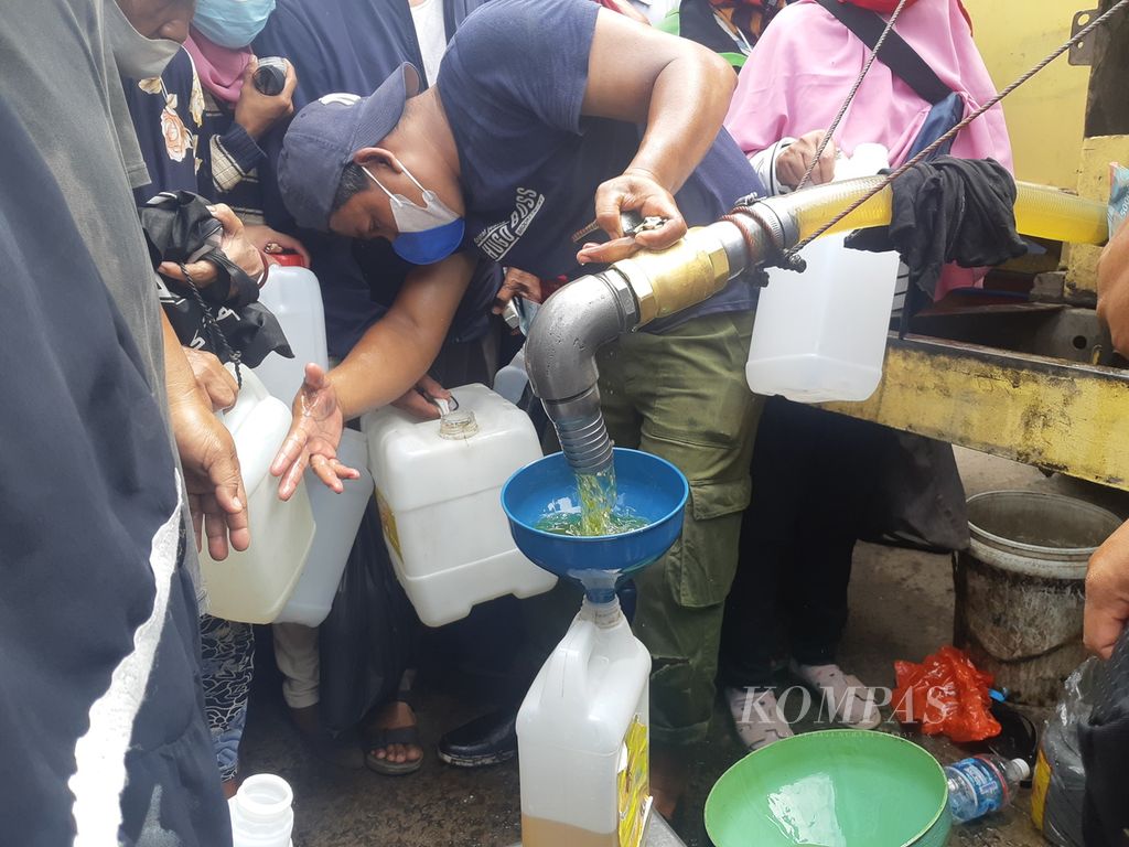 Seorang petugas menuangkan minyak curah ke dalam jeriken milik warga yang mengantre minyak goreng di Pasar Alang-Alang Lebar, Palembang, Sumatera Selatan, Sabtu (5/3/2022). Ratusan orang mengatre untuk mendapatkan minyak yang sampai saat ini sulit didapat.