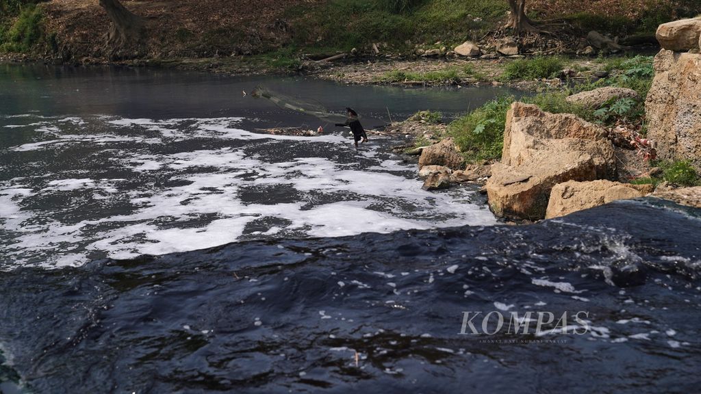 Dani menjaring ikan di Curug Parigi di aliran Sungai Cileungsi yang airnya menghitam dan menimbulkan bau tak sedap di Ciangsana, Kecamatan Gunung Putri, Kabupaten Bogor, Jawa Barat, Jumat (15/9/2023). 