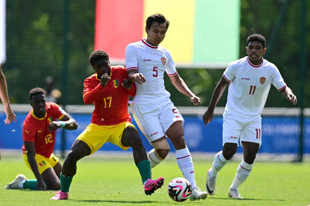 Indonesian defender, Komang Teguh (center), fights for the ball with Guinean midfielder, Issiaga Camara, during the 2024 Olympic playoff match in Clairefontaine-en-Yvelines, Thursday (9/5/2024).