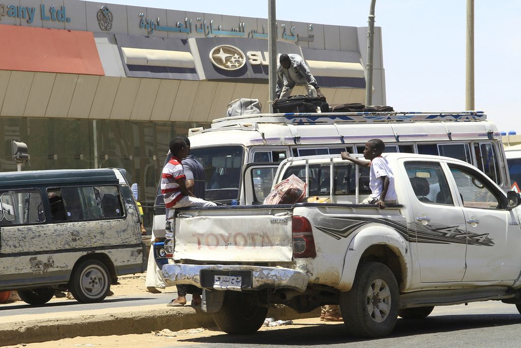 Orang-orang meninggalkan Khartum, Sudan, Selasa (18/4/2023), di tengah pertarungan di antara dua kekuatan bersenjata di negara itu. 