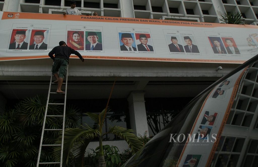 Two workers put up banners featuring five pairs of presidential and vice-presidential candidates participating in the 2004 presidential election at the General Election Commission Building in Jakarta on Tuesday (15/6/2004).
