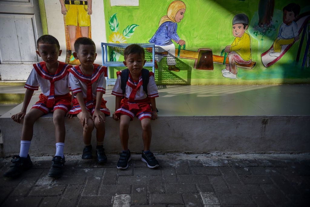 Tiga orang anak duduk dengan latar belakang mural bertema permainan anak-anak di SDN Pulau Untung Jawa 01 Pagi, Kepulauan Seribu, Jakarta, Senin (15/5/2023).
