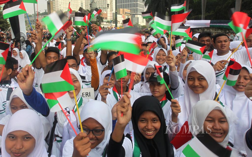 Sejumlah pelajar Indonesia mengibarkan bendera Indonesia dan Palestina saat berlangsungnya acara Walk for Peace and Humanity di kawasan hari bebas kendaraan bermotor (HBKB) Bundaran HI, Jakarta, Minggu (14/10/18). 