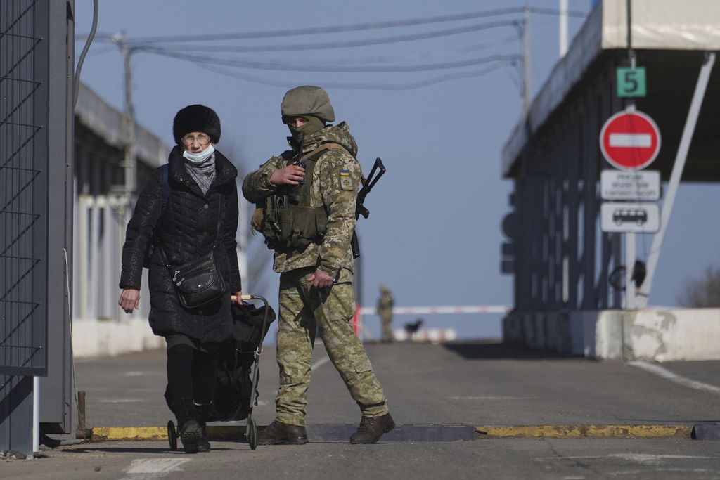 Seorang perempuan melintas pos pemeriksaan dari wilayah yang dikuasai kelompok separatis menuju area yang dikuasai tentara Ukraina di Novotroitske, Ukraina timur, Senin (21/2/2022). 
