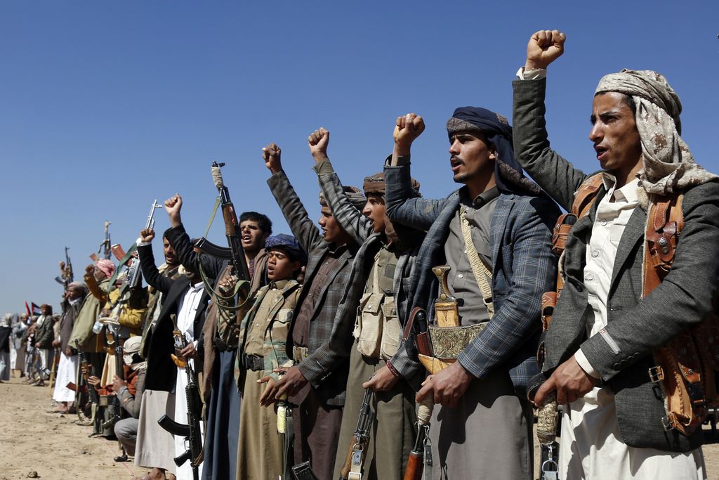 Anggota kelompok Houthi, sambil memegang senjata, berunjuk rasa di dekat Sana'a, Yaman, 14 Januari 2024, mengecam serangan Amerika Serikat dan Inggris terhadap fasilitas-fasilitas militer Houthi.  