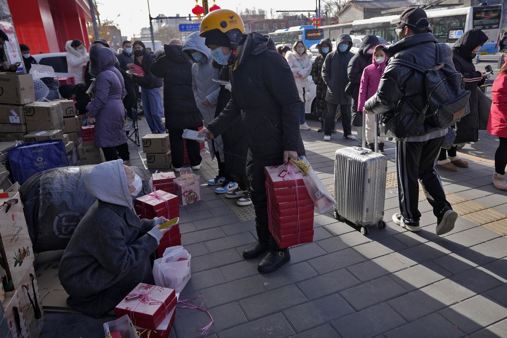 Seorang ojek online mengantarkan pesanan makanan konsumen saat banyak orang sedang antri di luar toko untuk membeli kue Tahun Baru Imlek di Beijing, Selasa (17/1/2023). 
