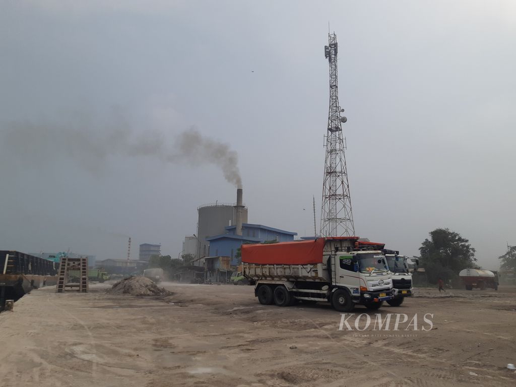 Aktivitas bongkar muat di Pelabuhan Marunda, Jakarta Utara, Jumat (1/4/2022) sore. Asap tampak membubung tinggi dari salah satu pabrik yang beroperasi di dalam Kawasan Berikat Nusantara.