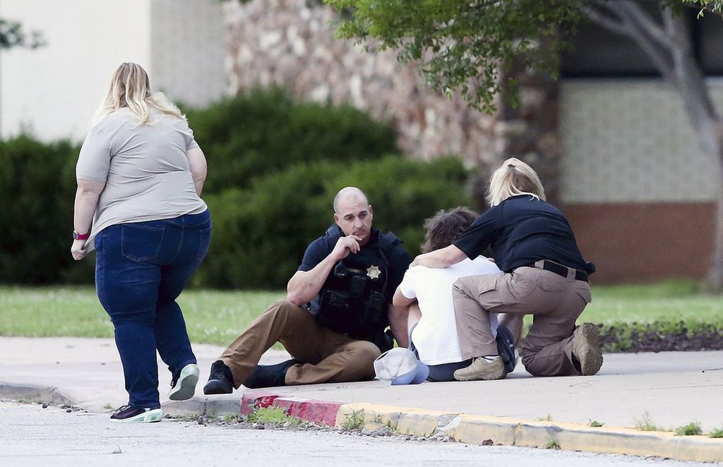 Kepolisian Tulsa berbicara dengan seorang pemuda di Memorial High School, saat tengah menunggu evakuasi anggota keluarganya dari lokasi penembakan di Tulsa, Oklahoma, AS, Rabu (1/6/2022) waktu setempat. Beberapa hari sebelumnya, sebanyak 19 siswa SD dan dua guru menjadi korban penembakan massal di Texas.