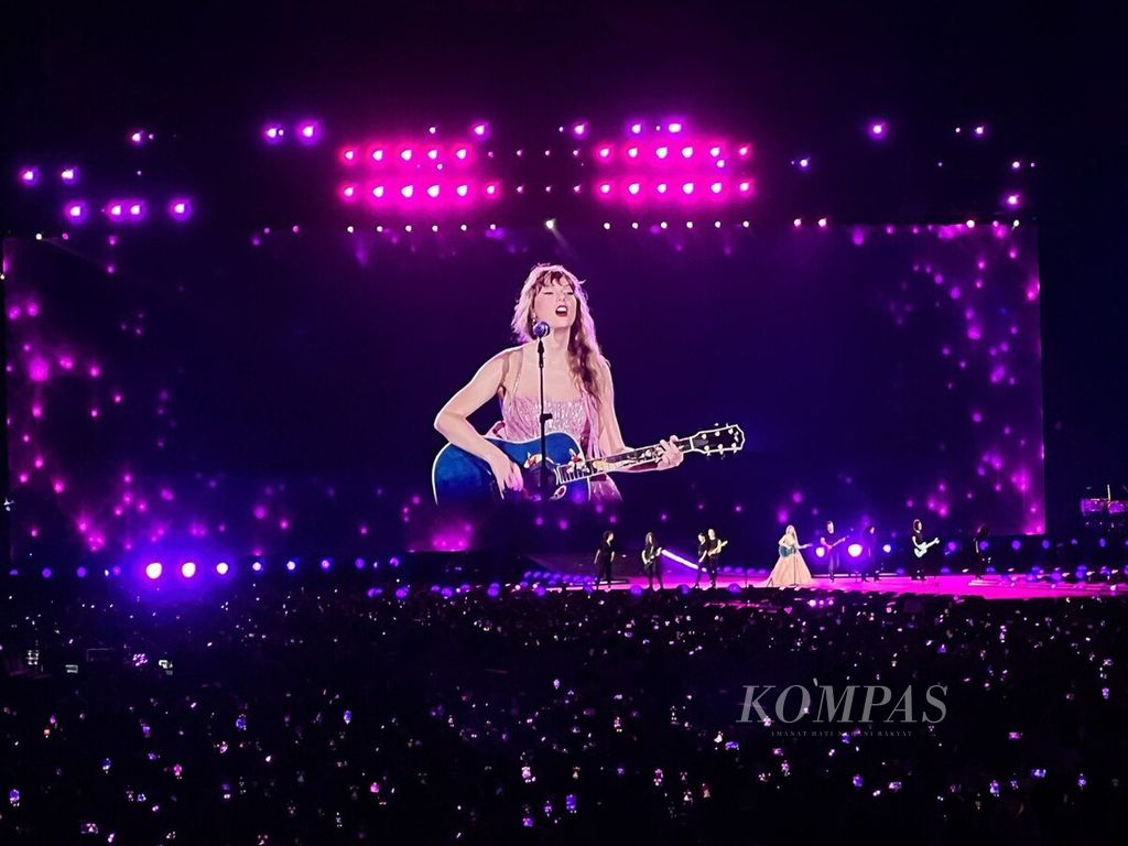 Di hadapan ribuan penggemarnya, Taylor Swift menyanyikan lagu sambil memainkan gitar dalam The Eras Tour di National Stadium, Singapura, Senin (4/3/2024). Konser Senin lalu adalah satu dari enam rangkaian konser berturut-turut Taylor Swift di Singapura.