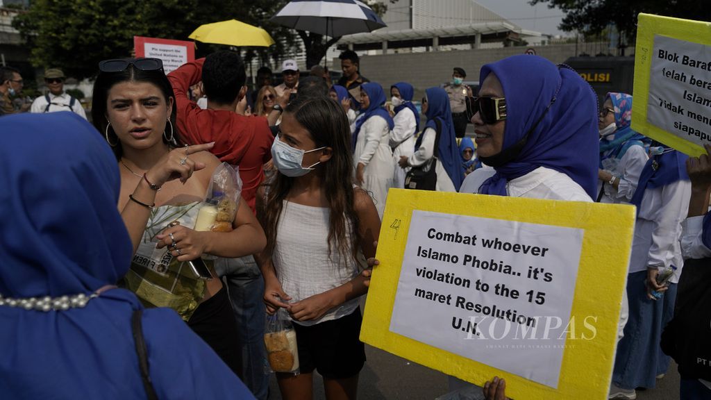 Turis asal Lithuania ikut berfoto dalam aksi damai hentikan Islamofobia di depan Kedutaan Amerika Serikat di Jakarta, Rabu (28/7/2022). Majelis Umum PBB menyetujui resolusi yang menetapkan tanggal 15 Maret sebagai Hari Internasional Melawan Islamofobia. 