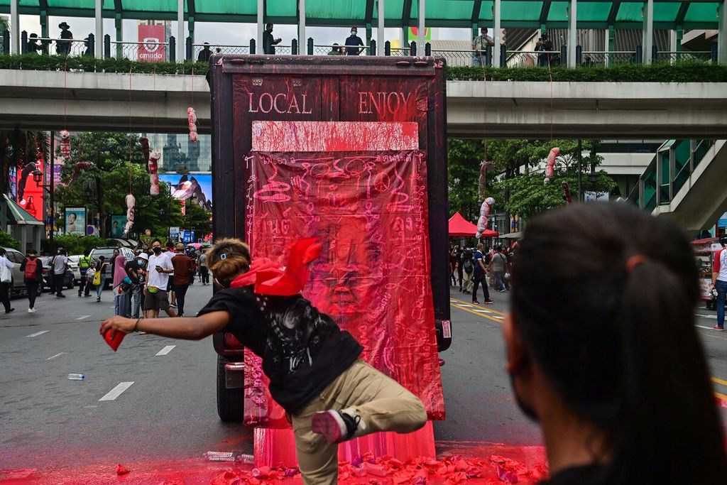 Seorang pengunjuk rasa melemparkan sekantong cat merah ke bagian belakang truk yang terpasang gambar yang mirip dengan Perdana Menteri Thailand Prayut Chan-O-Cha di Bangkok, Thailand, Jumat (3/9/2021).