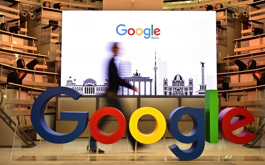 Foto yang diambil pada 22 Januari 2019 ini memperlihatkan seorang tengah berjalan di belakang logo Google di kantor perwakilan perusahaan teknologi ini di Berlin, Jerman.  
