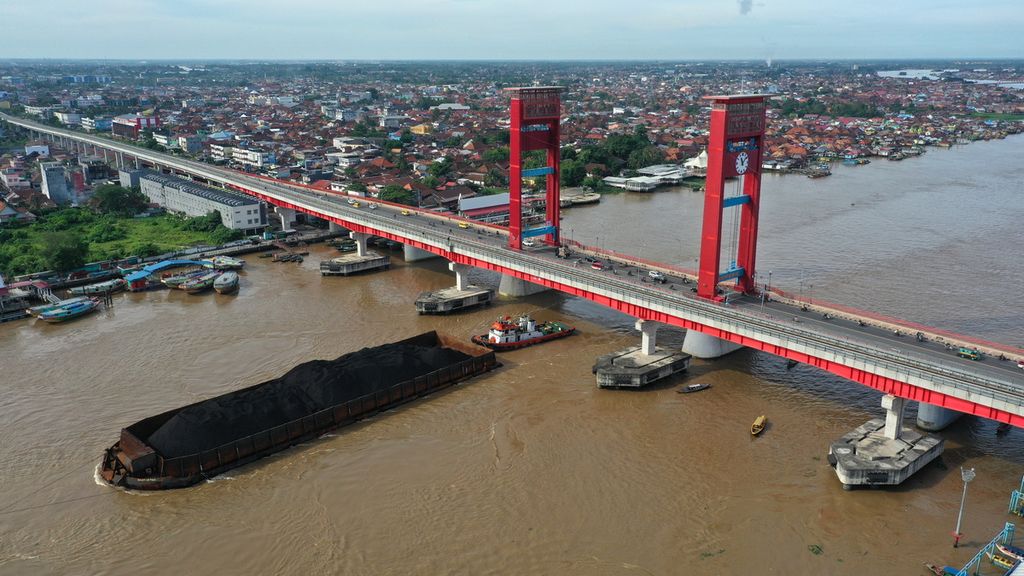 Tongkang bermuatan batubara melintasi Jembatan Ampera di Kota Palembang, Sumatera Selatan, Minggu (26/3/2023). Bank Dunia memperkirakan harga rata-rata batubara dunia pada 2023 turun 42 persen secara tahunan menjadi 200 dollar AS per ton.