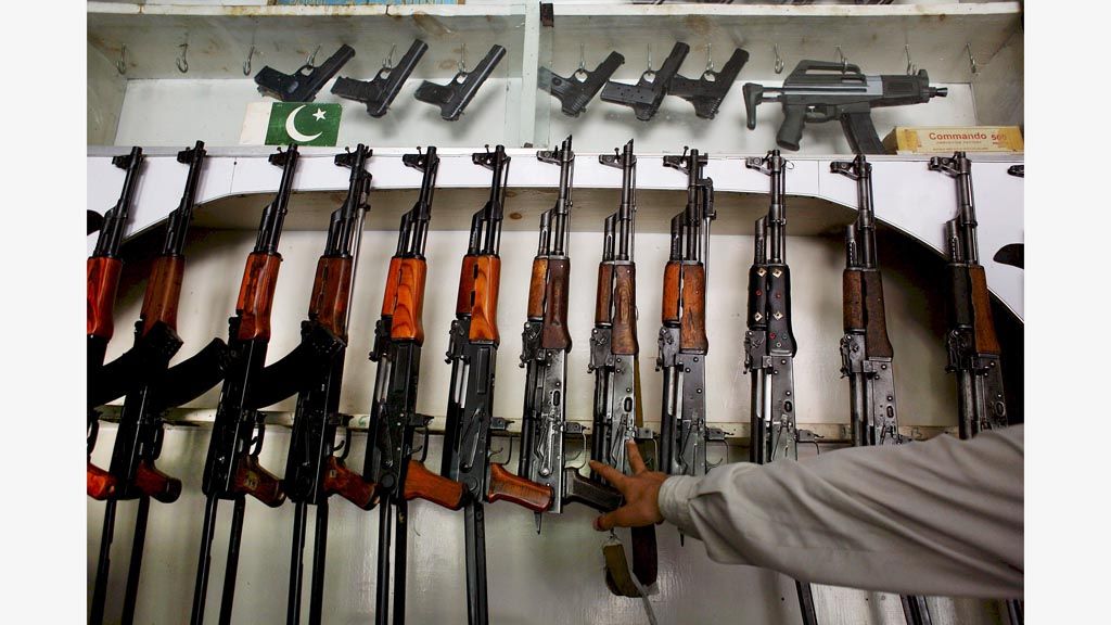 Penjaga toko  memperlihatkan deretan senapan AK-47 buatan Pakistan, China, dan Rusia di daerah Sakhacot, Pakistan barat, 10 September 2006. Toko-toko kecil memproduksi dan menjual ribuan senapan di area perbatasan Pakistan-Afghanistan.