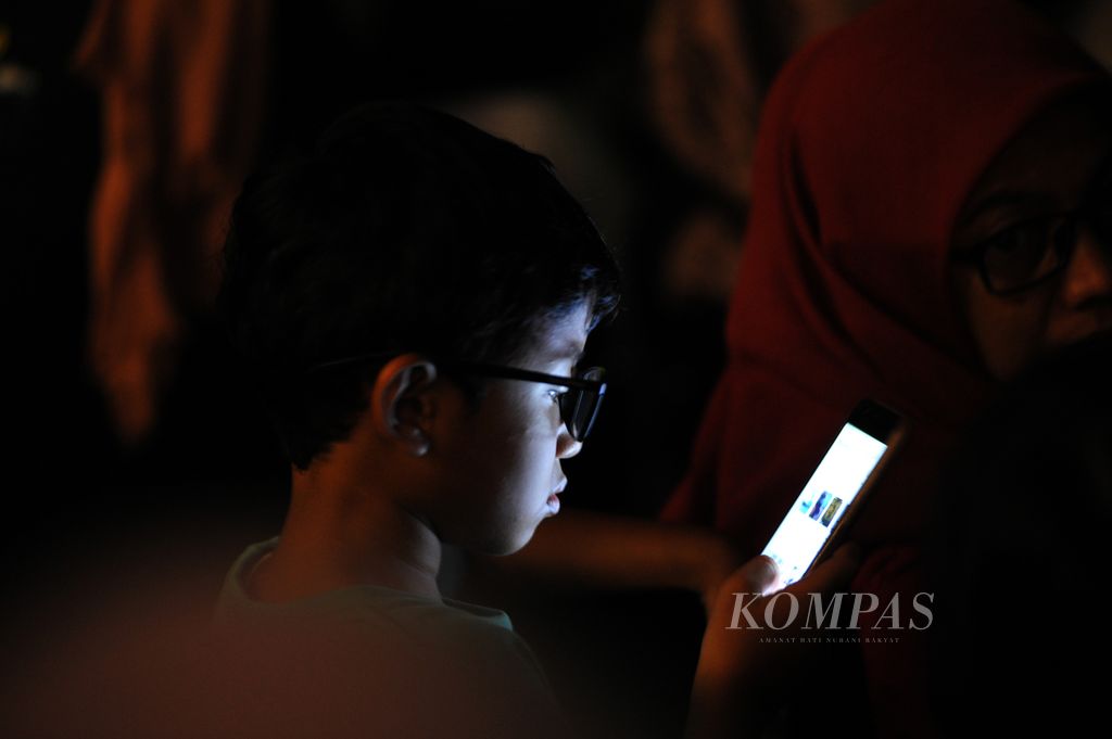 A child uses a gadget during the Inspirasi Perempuan Indonesia Fest 2022 event at The Kasablanka Main Hall, Mal Kota Kasablanka, South Jakarta on Saturday (17/12/2022).