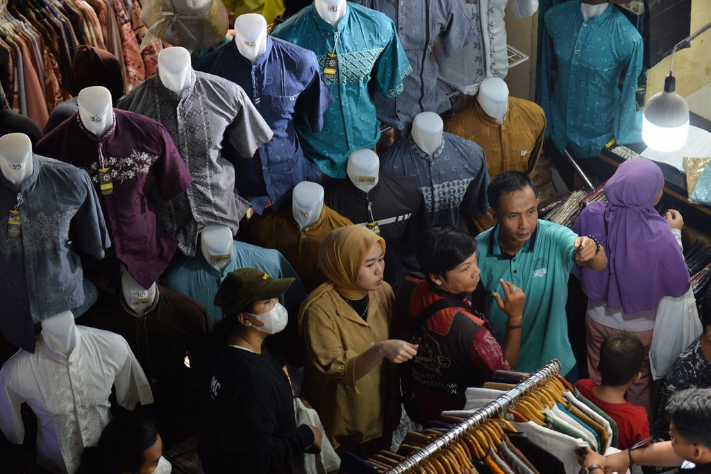 Residents choose clothing displayed at one of the shops in Tanah Abang Market, Central Jakarta, on Sunday (9/4/2023). Two weeks before Eid al-Fitr in 2023, residents began to flood Tanah Abang Market to buy new clothes. Some merchants estimate that the peak increase in revenue will occur during Eid al-Fitr as holiday allowances are distributed.