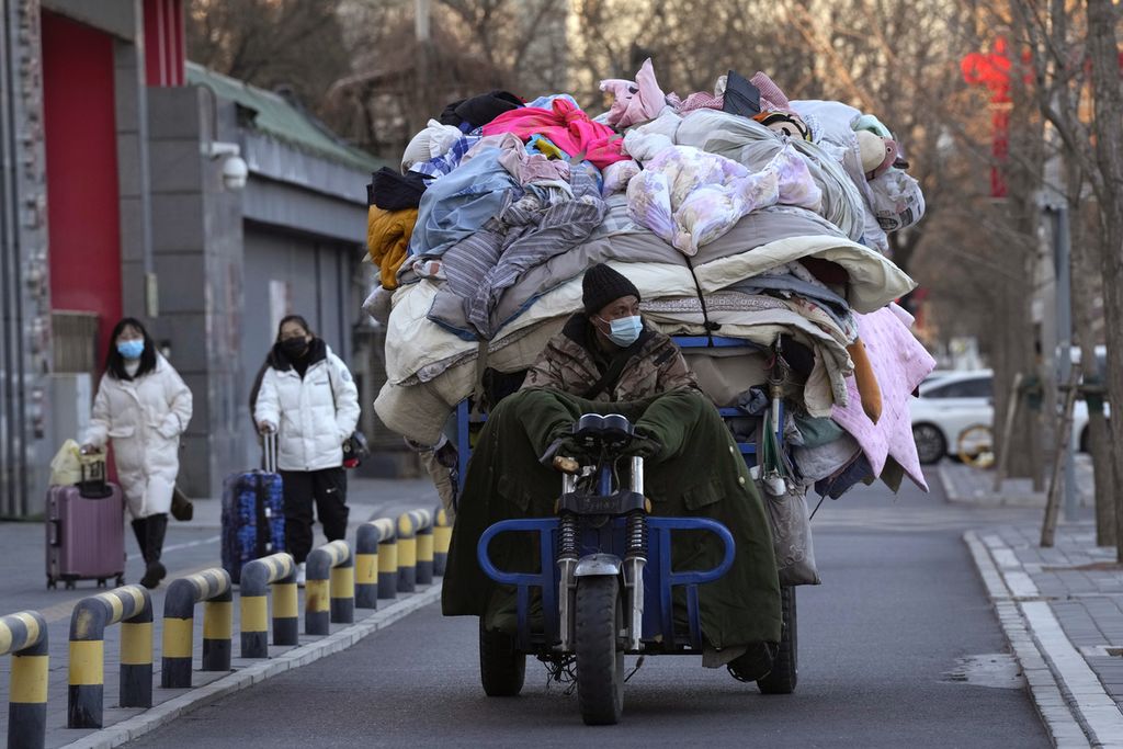 Seorang laki-laki mengangkut selimut bekas dan bahan kain lain di Beijing, China, pada Jumat, 30 Desember 2022. 