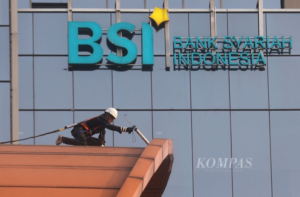 Pekerja melakukan perawatan sebuah bangunan dengan latar belakang gedung Bank Syariah Indonesia di kawasan Cawang, Jakarta, Jumat (19/7/2024). 