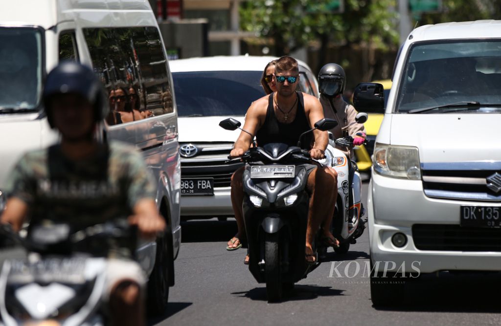 Turis asing berboncengan sepeda motor tanpa mengenakan helm di kawasan Kuta, Bali, Sabtu (18/3/2023). Masih dijumpai turis asing yang tidak menaati aturan lalu lintas saat berkendara di Bali.