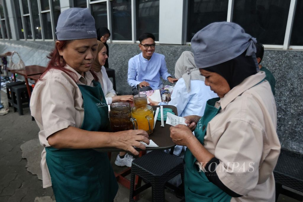 Pekerja menyajikan minuman yang dipesan pelanggan di Uma Oma Cafe, kawasan Blok M, Jakarta, Jumat (29/3/2024). Beberapa pelayan yang bekerja di kafe ini merupakan oma atau nenek. 