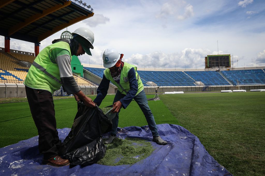 Dua pekerja membereskan potongan rumput di Stadion Si Jalak Harupat, Kabupaten Bandung, Senin (3/4/2023). Perbaikan Stadion Si Jalak Harupat tetap berlanjut meski Indonesia batal menjadi tuan rumah Piala Dunia U-20. Proses renovasi stadion tersebut telah memasuki tahap akhir. 