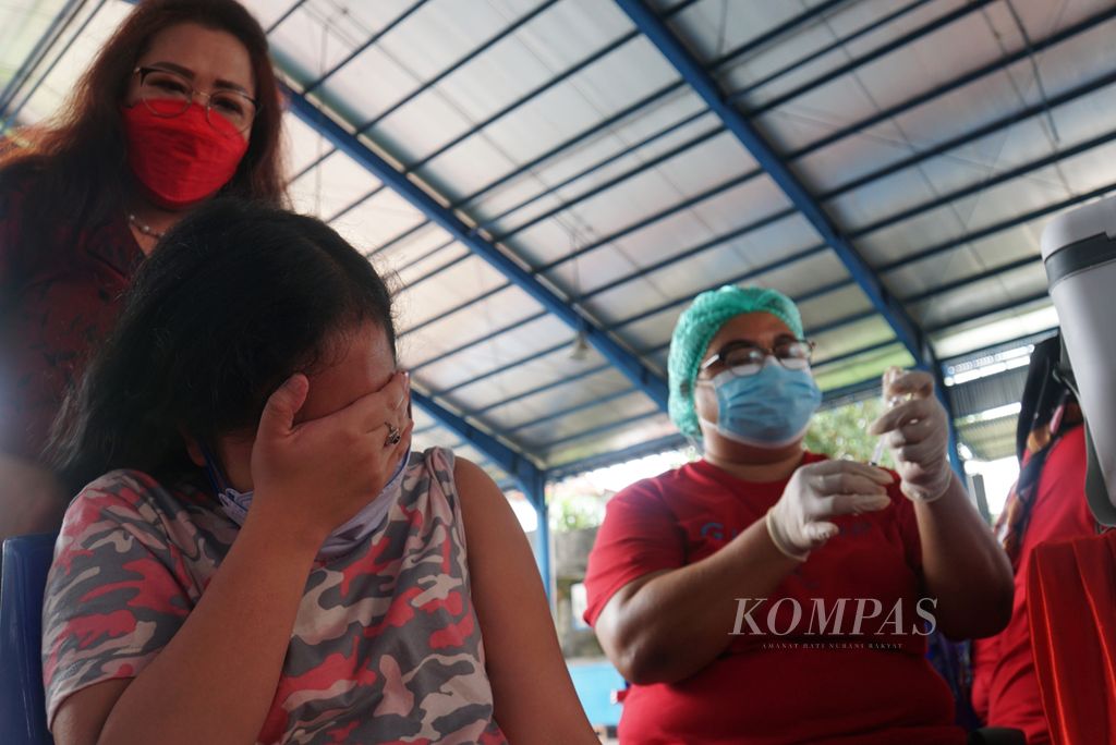 Seorang siswa menutup matanya karena takut ketika akan mendapat suntikan pertama vaksin Covid-19 di SMA Eben Haezar, Manado, Sulawesi Utara, Senin (5/7/2021).