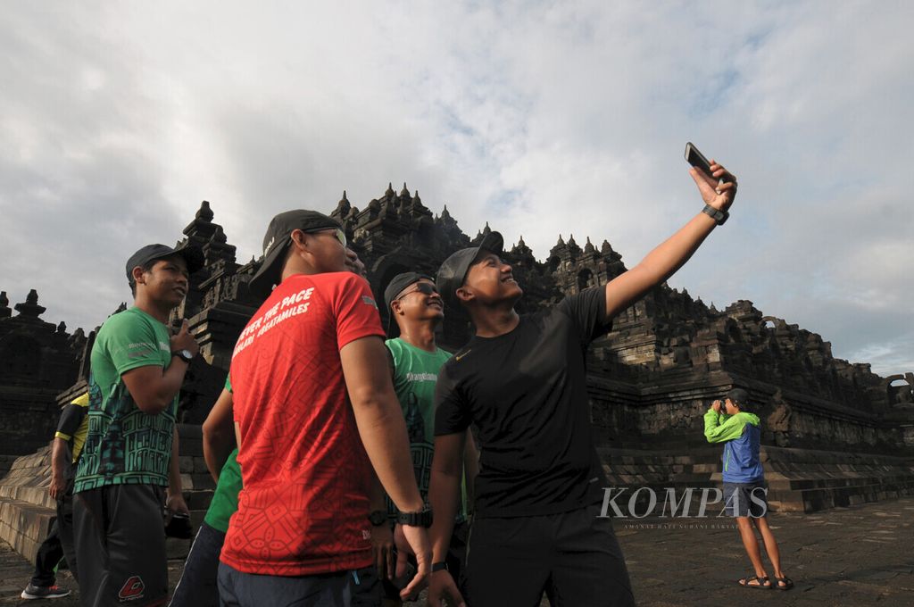 Runners take photos on the sidelines of light jogging for about 3 kilometers while enjoying the view at Borobudur Temple, Magelang, Saturday (11/18/2019).