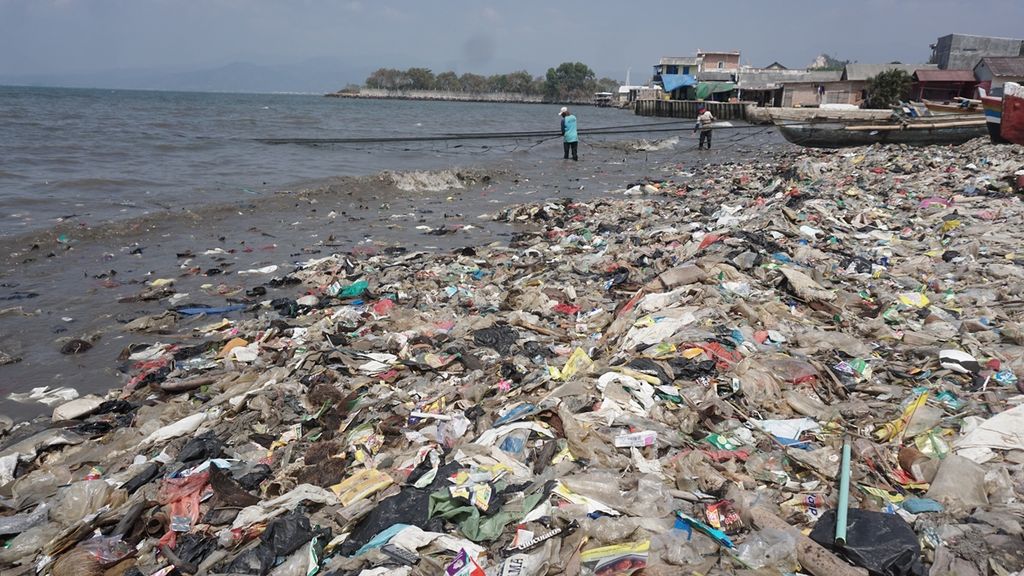 Nelayan menjaring ikan di antara tumpukan sampah di kawasan pesisir Kelurahan Sukaraja, Kecamatan Bumiwaras, Kota Bandar Lampung, Lampung, Jumat (13/9/2019). 