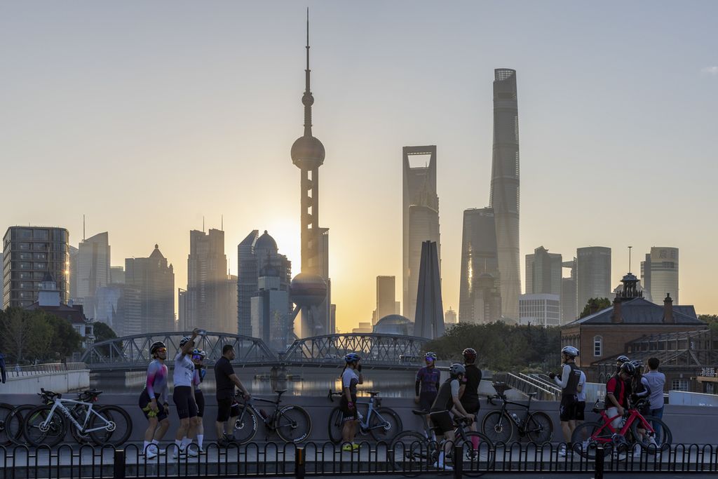 Para pesepeda berswafoto dengan latar belakang pemandangan matahari terbit di balik gedung-gedung pencakar langit di Pudong, pusat komersial dan keuangan China, di Shanghai, 3 November 2023. 