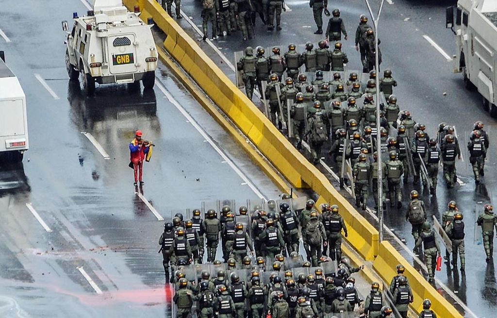 Di tengah kepungan polisi antihuru-hara Venezuela, Wuilly Arteaga (23) memainkan biola dalam unjuk rasa menentang Presiden Nicolas Maduro di Caracas, Venezuela, 24 Mei lalu. 