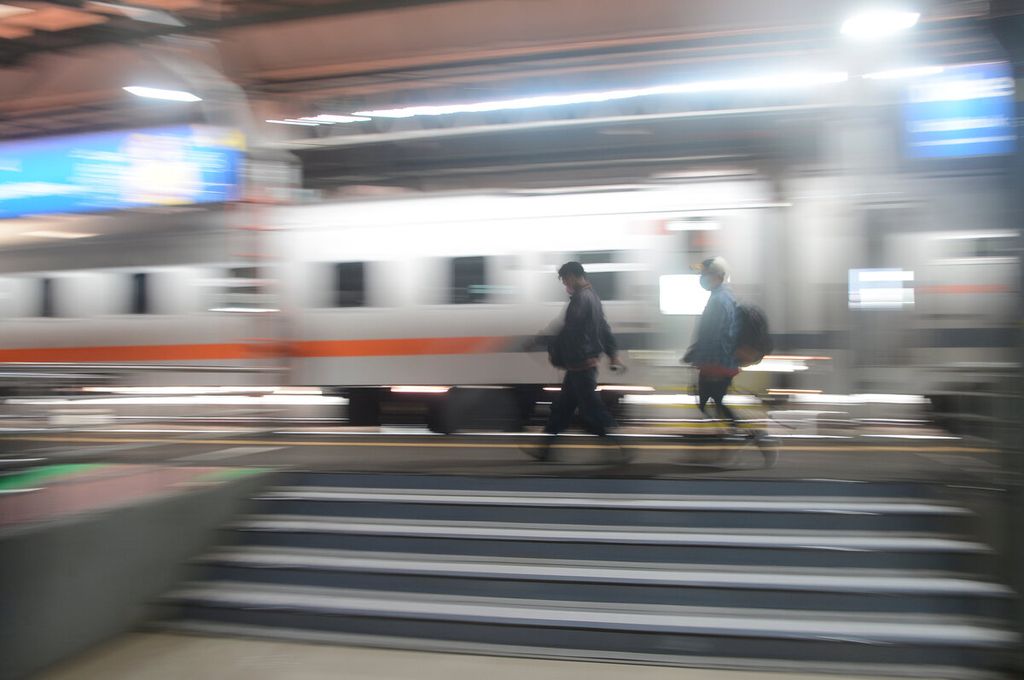 Penumpang kereta api melintasi rangkaian gerbong di Stasiun Tawang, Kota Semarang, Jawa Tengah, Rabu (9/3/2022).