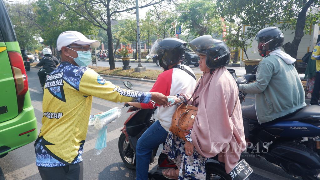Petugas membagikan masker kepada warga yang melintas di Jalan Brigjen Hasan Basri, Kota Banjarmasin, Kalimantan Selatan, Senin (2/10/2023). 