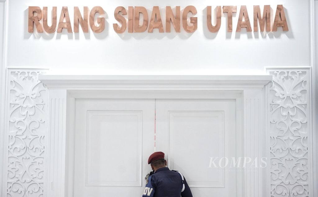 Seorang petugas keamanan Komisi Pemilihan Umum mengintip ruangan saat berjaga di luar ketika digelar Rapat Koordinasi KPU dengan Tim Pasangan Calon dan Partai Politik dalam Pelaksanaan Kampanye Metode Rapat Umum di Kantor Komisi Pemilihan Umum, Jakarta, Minggu (14/1/2024).