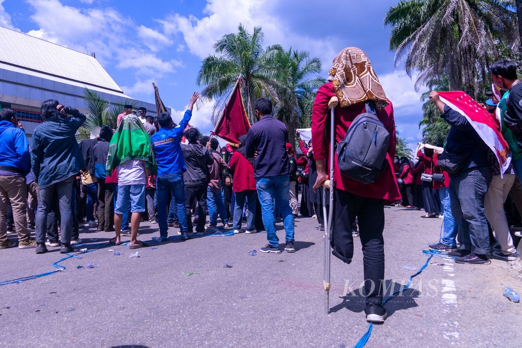 Seorang mahasiswa dengan tongkat mengikuti aksi nasional pada Senin (11/4/2022), di Kendari, Sulawesi Tenggara, bersama ribuan mahasiswa lainnya. Mereka menuntut pengentian wacana tiga periode Presiden, penundaan pemilu, penurunanan harga minyak, dan sebagainya. Aksi ini berujung bentrok dengan aparat kepolisian.